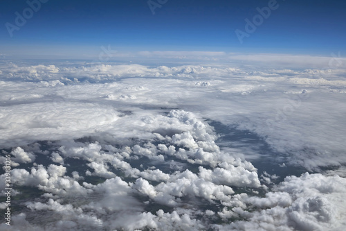 White clouds against a blue sky, shot from a plane flying above the clouds