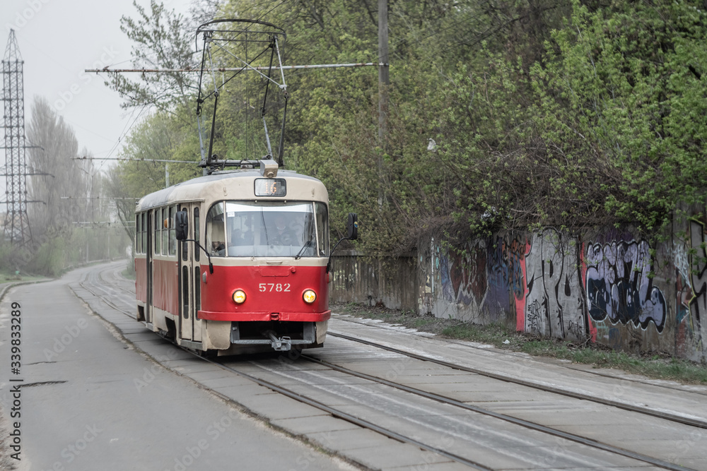 Kyiv, Ukraine - April, 2020: Old red soviet tram in industrial area in cluody day.