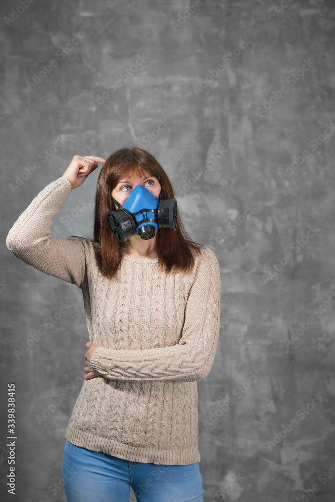 Girl in blue respirator thinks about epidemic on grey background. Isolation and virus protection concept with copy space. Girl in blue respirator thinks about epidemic on grey background. Isolation and virus protection concept with copy space.