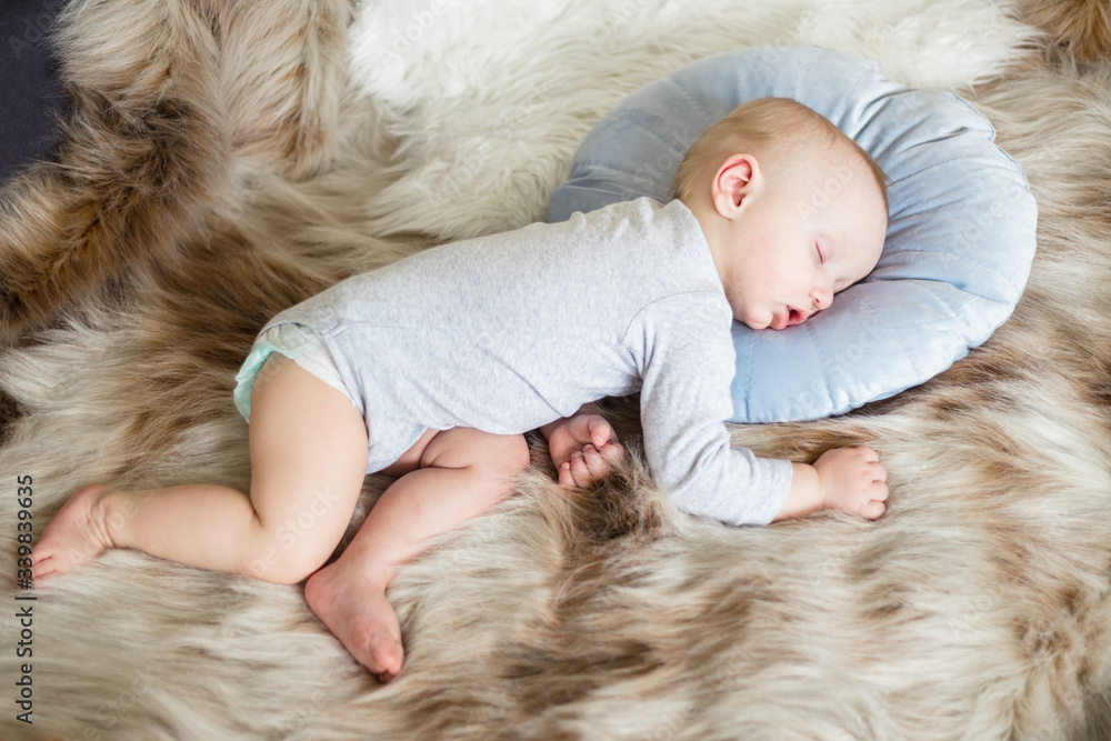 Little baby boy sleeping on a sofa on blue pillow and artificial fur Little baby boy sleeping on a sofa on blue pillow and artificial fur