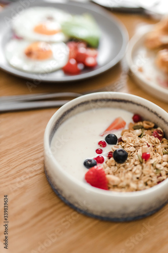 porridge and granola with nuts and berries in a plate on a wooden table
