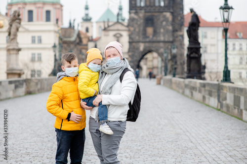 Woman with her children wearing medical masks stand on empty Charles Bridge in Prague. Coronavirus epidemic concept
