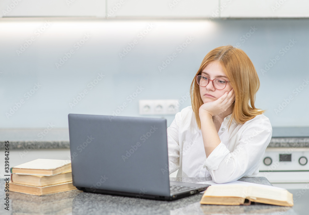 Pensive girl is doing homework with laptop at home. Distance learning Pensive girl is doing homework with laptop at home. Distance learning