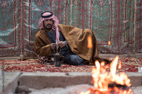Canvas-taulu Bedouin man wearing traditional clothes praying with a tasbih while drinking tea
