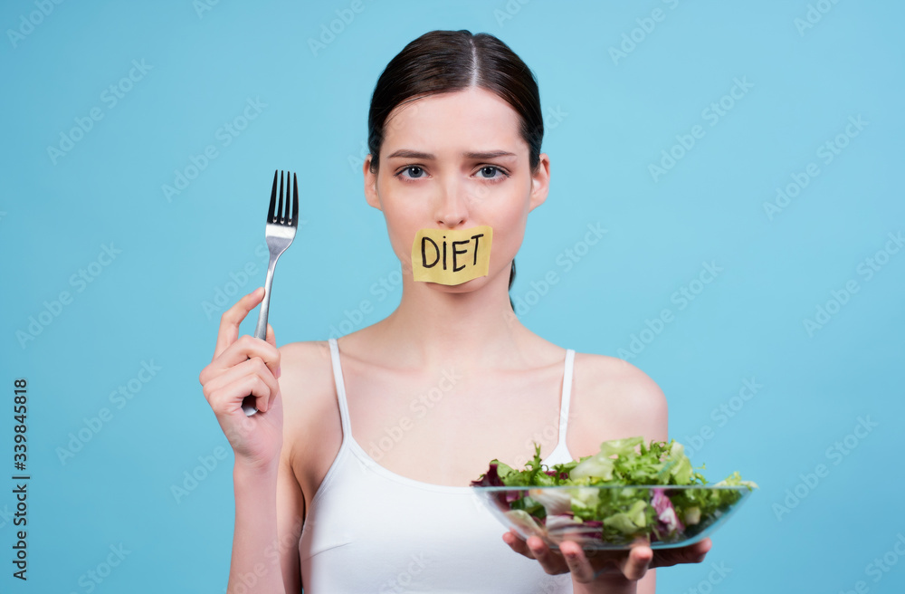 Hungry young woman with sticky mouth and bowl of green salad. Hungry young woman with sticky mouth and bowl of green salad.
