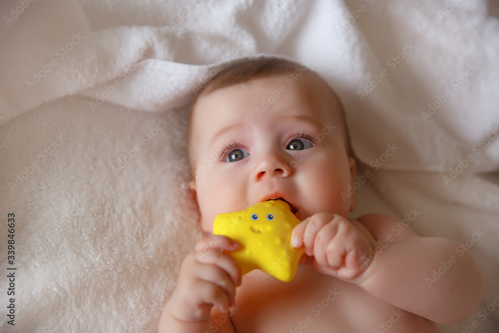baby in a towel after bathing lying on the bed at home playing with a toy baby in a towel after bathing lying on the bed at home playing with a toy