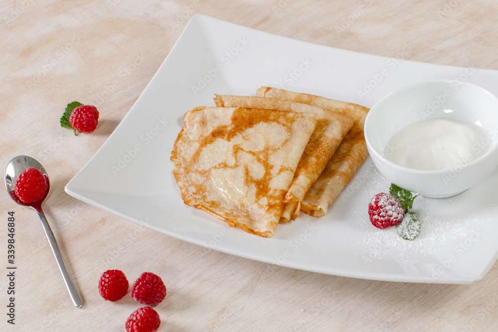 Pancakes with sour cream and raspberries