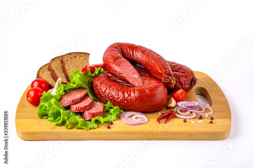  sausage on a cutting board with herbs and vegetables white background