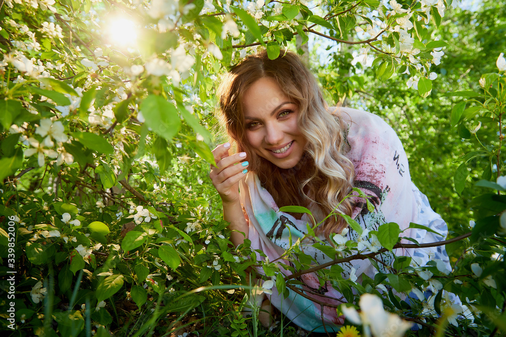 Portrait of a beautiful blonde girl with green eyes and blossoming apple tree with white flower in the park in a spring time Portrait of a beautiful blonde girl with green eyes and blossoming apple tree with white flower in the park in a spring time
