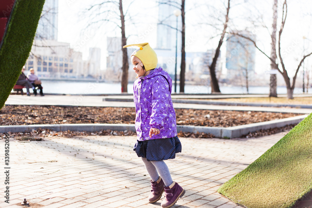 A girl in a hat and jacket walks on the street with her mother, the joy of walking, Park, traffic, smile, city, environment, growing up, learning the world, spring