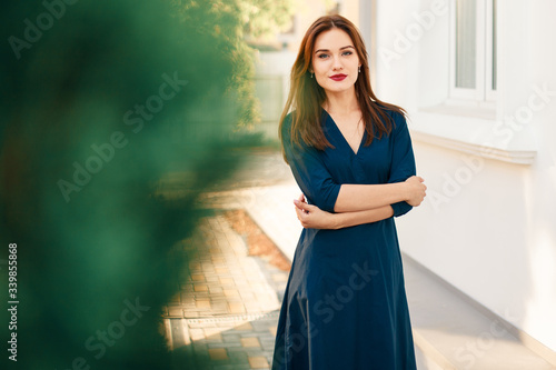 Red-haired model in a dark blue dress posing in the garden. photo