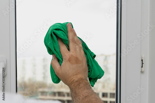 House cleaning. a man’s hand washes a window with a green rag