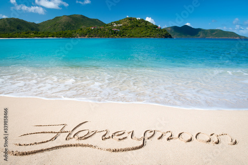 Romantic island honeymoon message written in smooth sand on bright tropical beach