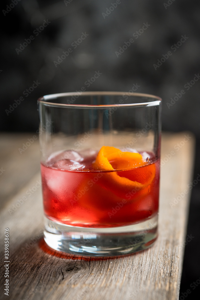 Red traditional old fashioned cocktail with orange zest on the rustic background. Selective focus. Shallow depth of field. Red traditional old fashioned cocktail with orange zest on the rustic background. Selective focus. Shallow depth of field.