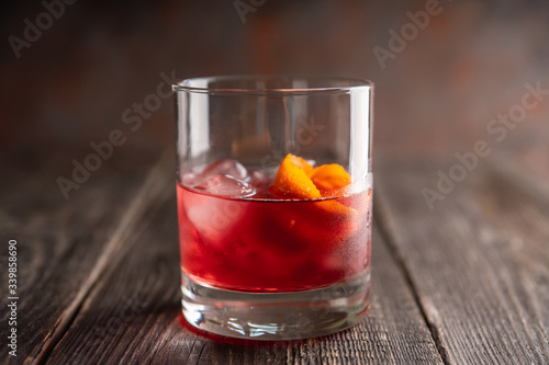 Red traditional old fashioned cocktail with orange zest on the rustic background. Selective focus. Shallow depth of field.