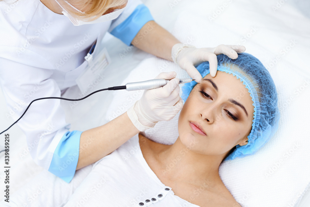 Professional beautician doing eyebrow tattoo at woman face. Permanent brow makeup in beauty salon, closeup. Cosmetology treatment Professional beautician doing eyebrow tattoo at woman face. Permanent brow makeup in beauty salon, closeup. Cosmetology treatment