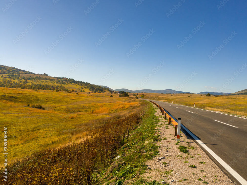 Autumn on the Klekovaca mountain near Bosanski Petrovac. Fall colors in the countryside. Mountain landscape. Grassy rural slopes with fields and trees in fall foliage in autumn.