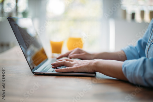 Detail of a woman typing on a laptop keyboard at home © Suteren Studio