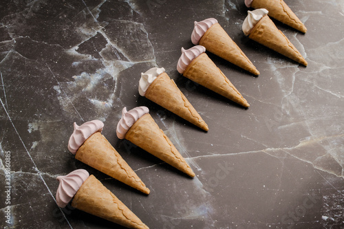 Small waffle ice cream cups with colored marshmallows on a black marble background