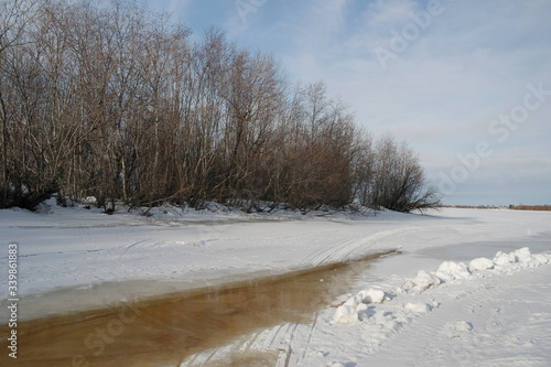 A small area of water between the shore and the edge of ice on a frozen river in early spring