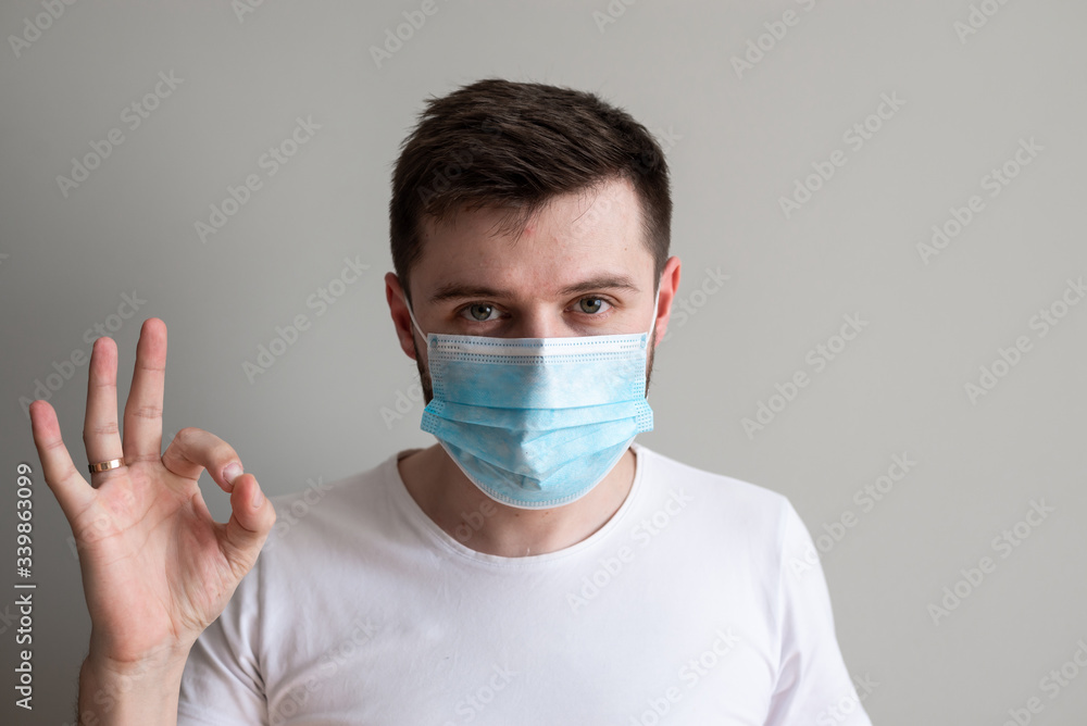 Handsome man showing okay gesture. Photo of healthy man wears protective mask against infectious diseases and flu. Health care concept. Handsome man showing okay gesture. Photo of healthy man wears protective mask against infectious diseases and flu. Health care concept.