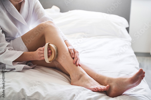 Female using an exfoliating body brush at home