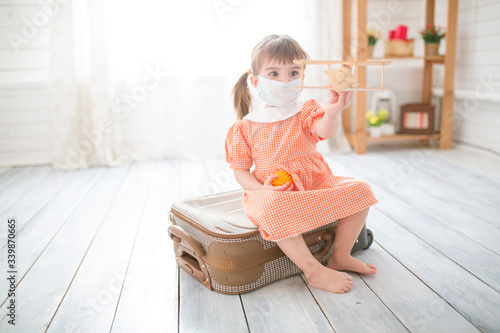 Little cute kid girl in quarantine at home dreams of traveling. photo