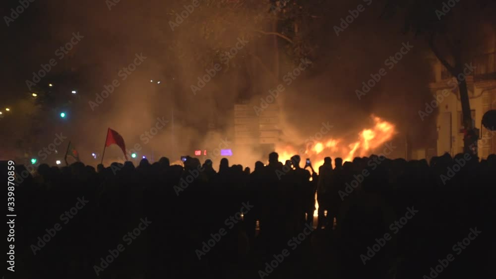 Crowds of revolutionary people involved in street riots with barricades and burning dumpsters in front of the police Crowds of revolutionary people involved in street riots with barricades and burning dumpsters in front of the police