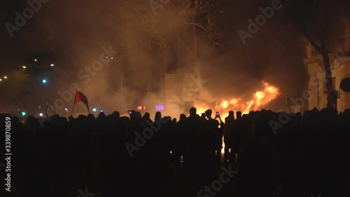 Crowds of revolutionary people involved in street riots with barricades and burning dumpsters in front of the police