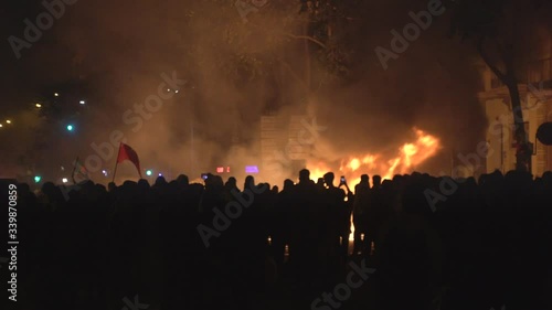 Crowds of revolutionary people involved in street riots with barricades and burning dumpsters in front of the police photo