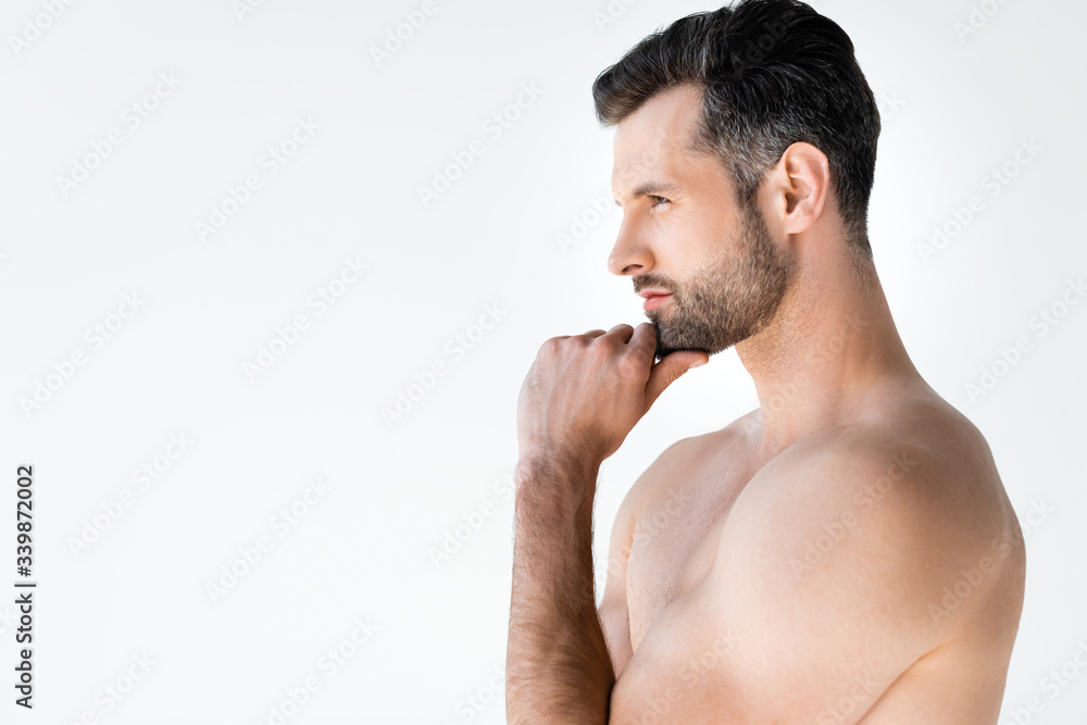 Fototapeta premium side view of shirtless man thinking and touching face isolated on white