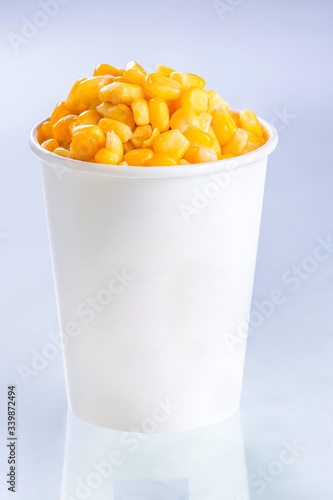 Boiled corn kernels in foam cup side view isolated on white background.