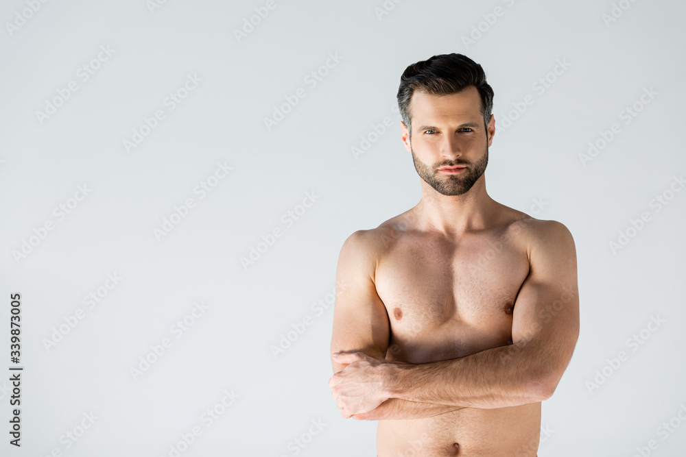 muscular man standing with crossed arms isolated on grey muscular man standing with crossed arms isolated on grey