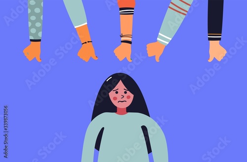 Dislike it concept. Unhappy young woman surrounded by hands with thumbs down at her. Concept of victim blaming, public disapproval, humiliation, abjection, guilt.
