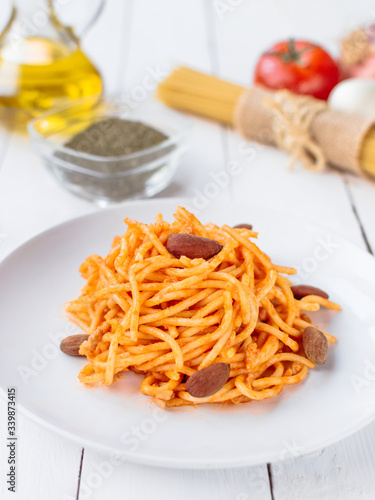 White plate with spaghetti on a white wooden table.