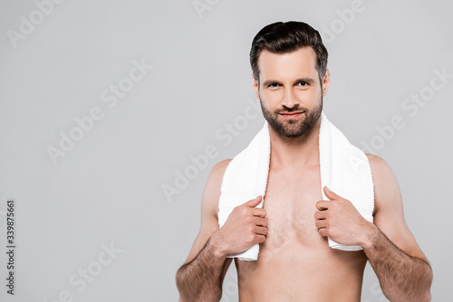 Photos cheerful and muscular man touching white towel isolated on grey