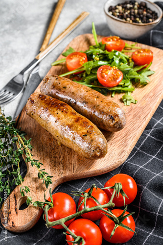 Barbecue grilled pork Sausages with a side dish of tomato salad and arugula. Gray background. Top view