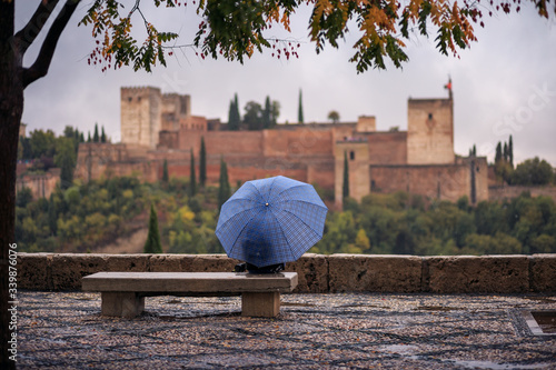 Tourist with umbrellas looking at the Alhambra from the Mirador de San Nicolas, a rainy day. photo