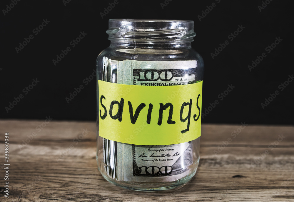 Glass jar with money and label save on table against . Space for text Glass jar with money and label save on table against . Space for text