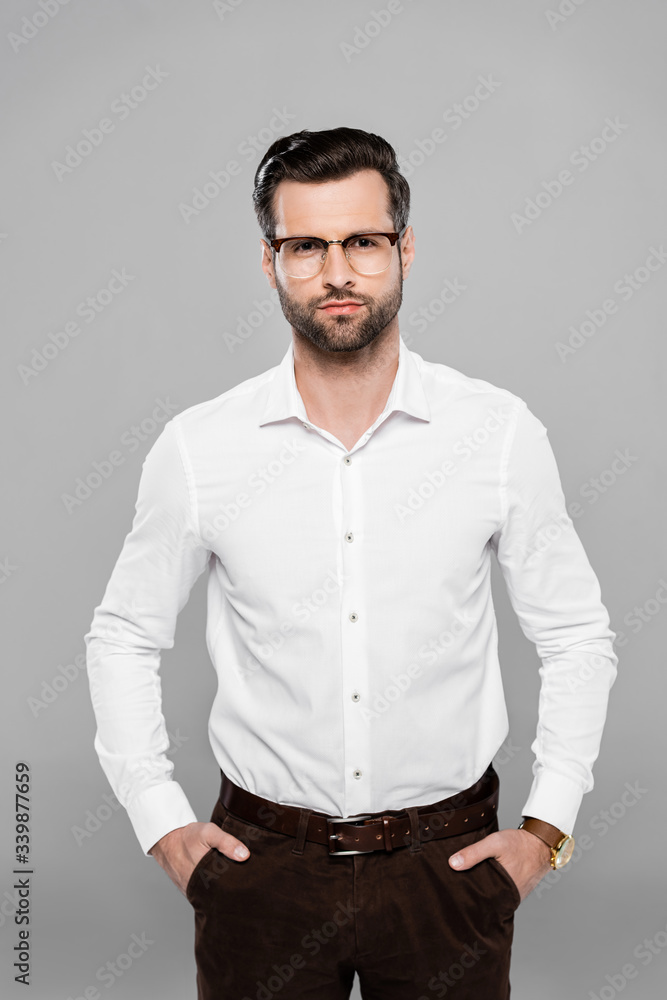bearded businessman in glasses standing with hands in pockets isolated on grey bearded businessman in glasses standing with hands in pockets isolated on grey