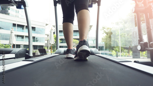 young woman running on treadmill in gym.