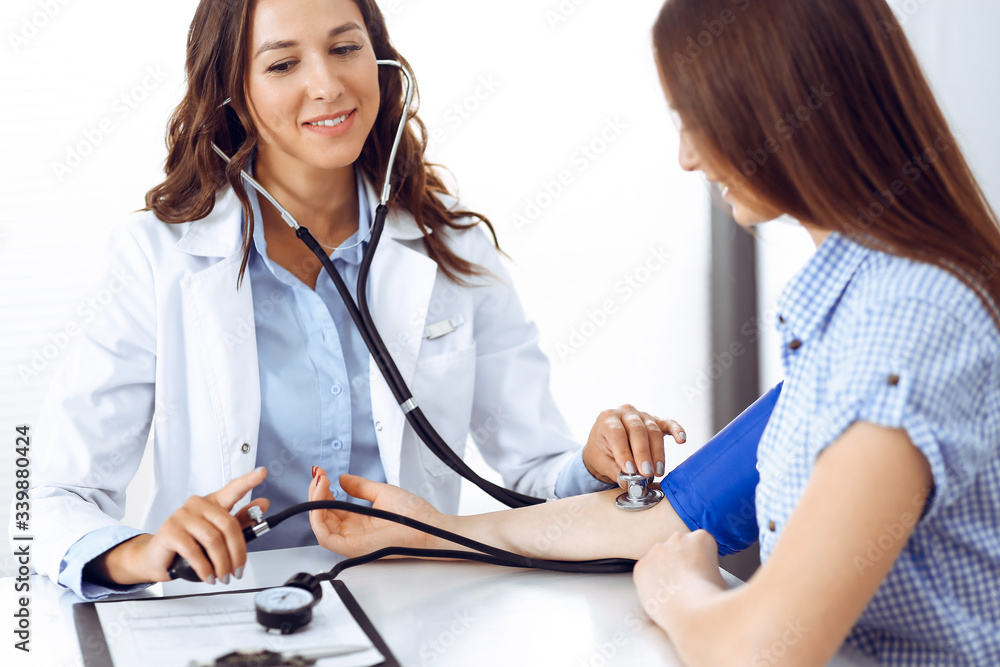 Doctor with a stethoscope in the hand examining her female patient. Health care, cardiology and medicine concepts Doctor with a stethoscope in the hand examining her female patient. Health care, cardiology and medicine concepts