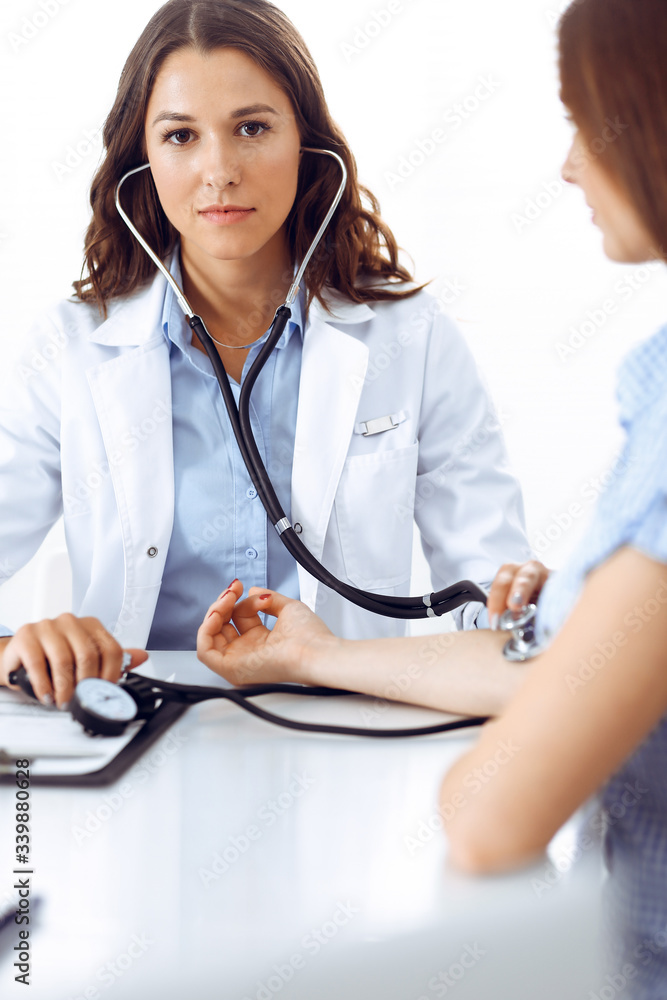 Doctor with a stethoscope in the hand examining her female patient. Health care, cardiology and medicine concepts Doctor with a stethoscope in the hand examining her female patient. Health care, cardiology and medicine concepts