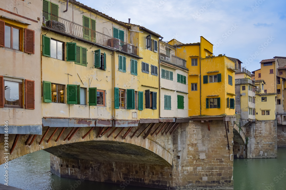 A close up of the colorful yellow and green shops that line the Ponte Vecchio that crosses the Arno River in Florence, Italy.