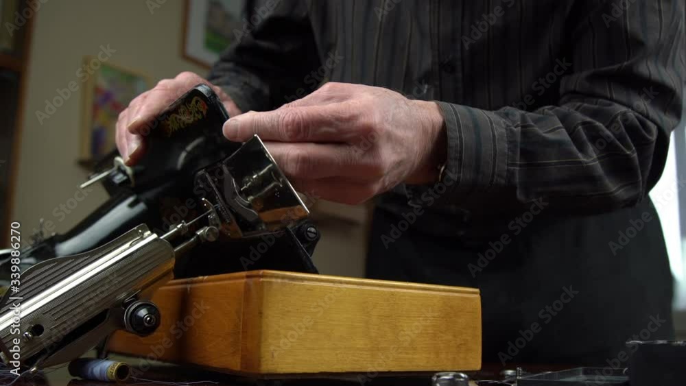 old man with wrinkles on hands fixes antique sewing machine using screwdriver from accessory box close view old man with wrinkles on hands fixes antique sewing machine using screwdriver from accessory box close view