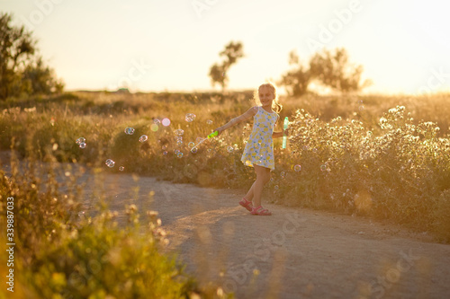 a girl in a field playing and blowing soap bubbles © Elena 