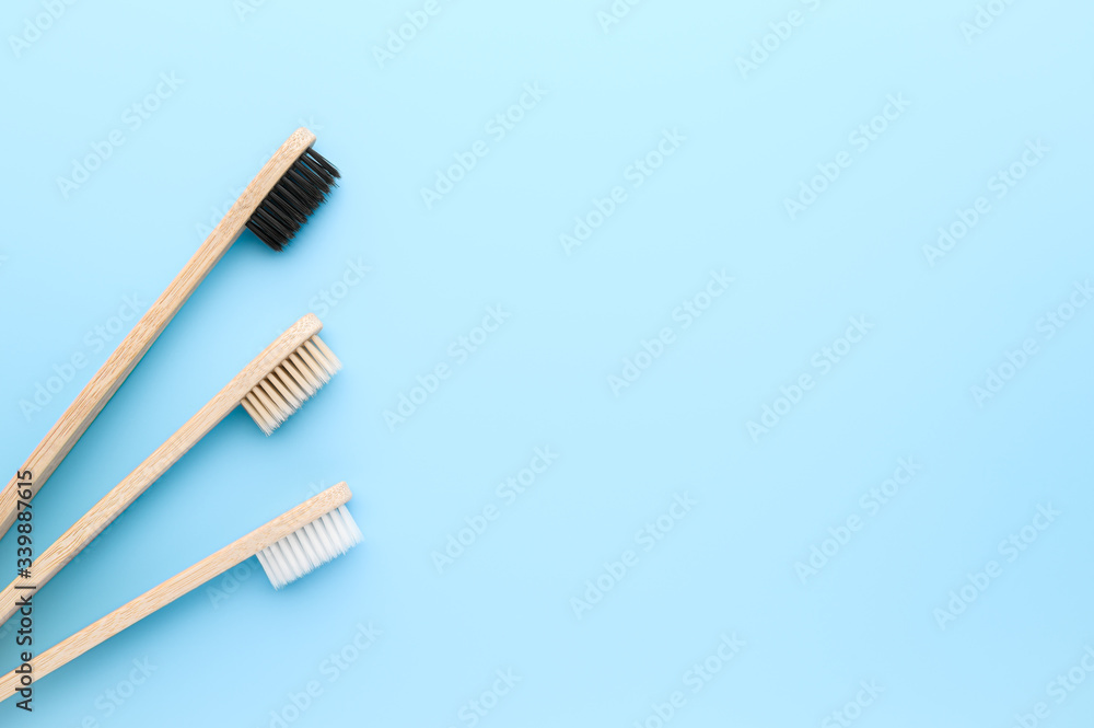 Zero waste and no plastic concept. Three eco friendly bamboo toothbrushes on a light blue surface. Top view, copy space, horizontal orientation. Layout natural organic hygiene products. Zero waste and no plastic concept. Three eco friendly bamboo toothbrushes on a light blue surface. Top view, copy space, horizontal orientation. Layout natural organic hygiene products.