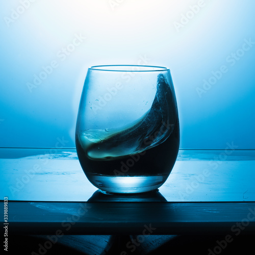 Splash of wine in a glass on a blue textured background.