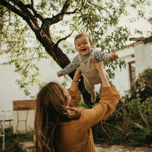 Mother holding her baby son up in the air, and baby laughing.