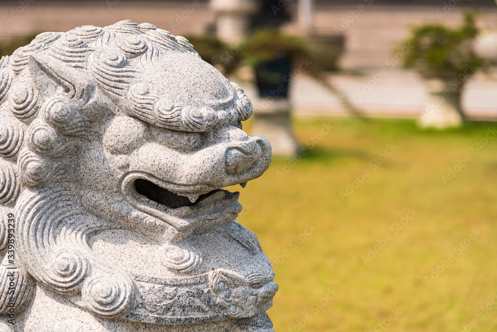 Closeup of Chinese lion sculpture in green garden.